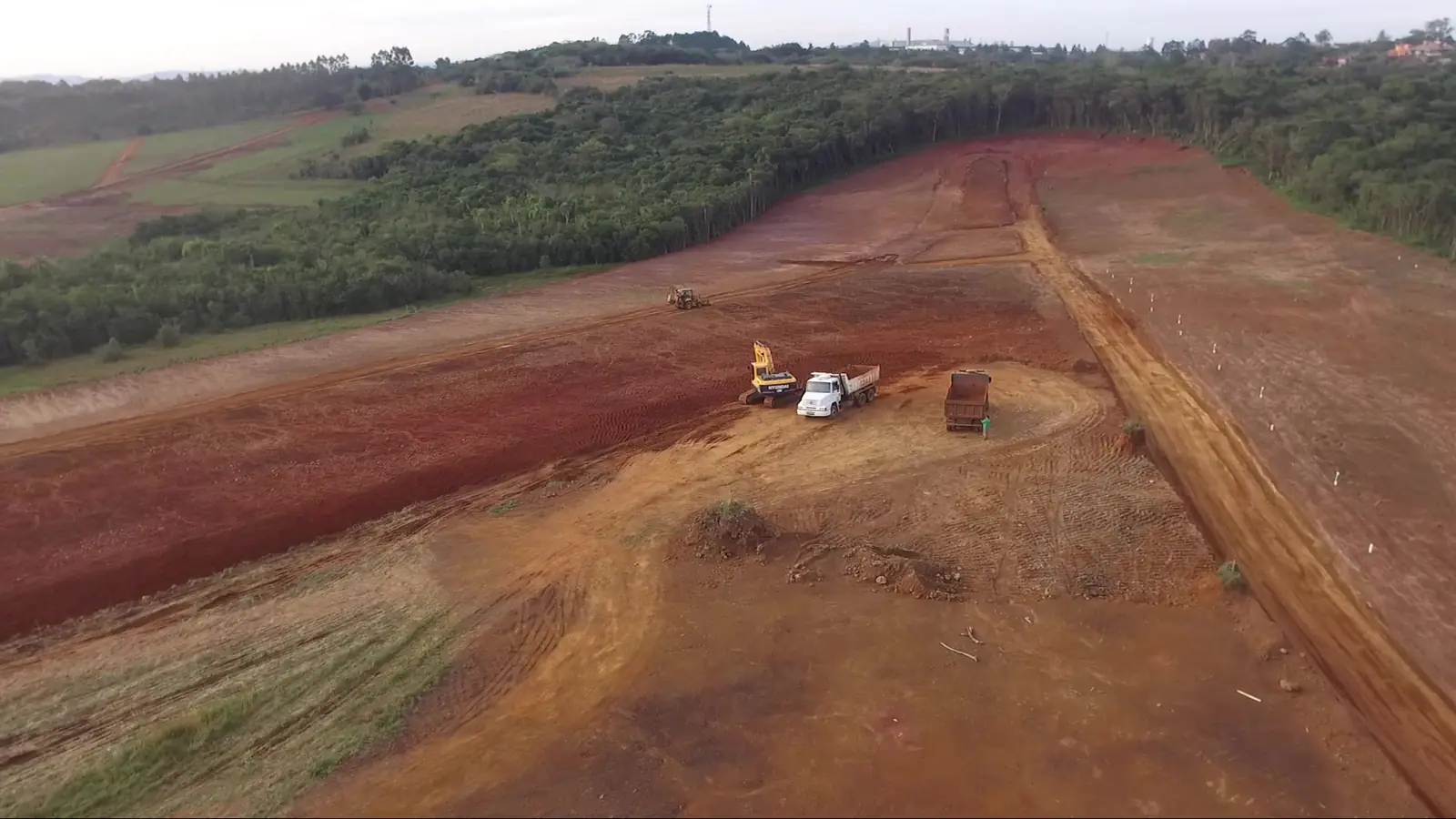 Vista aérea de área de terraplenagem com estradas de terra e máquinas ao fundo